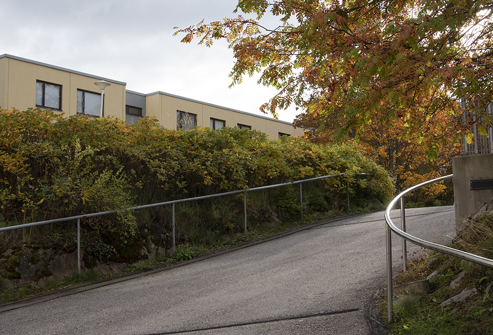 Asfaltoitu mäki ja mäen päällä kerrostalo