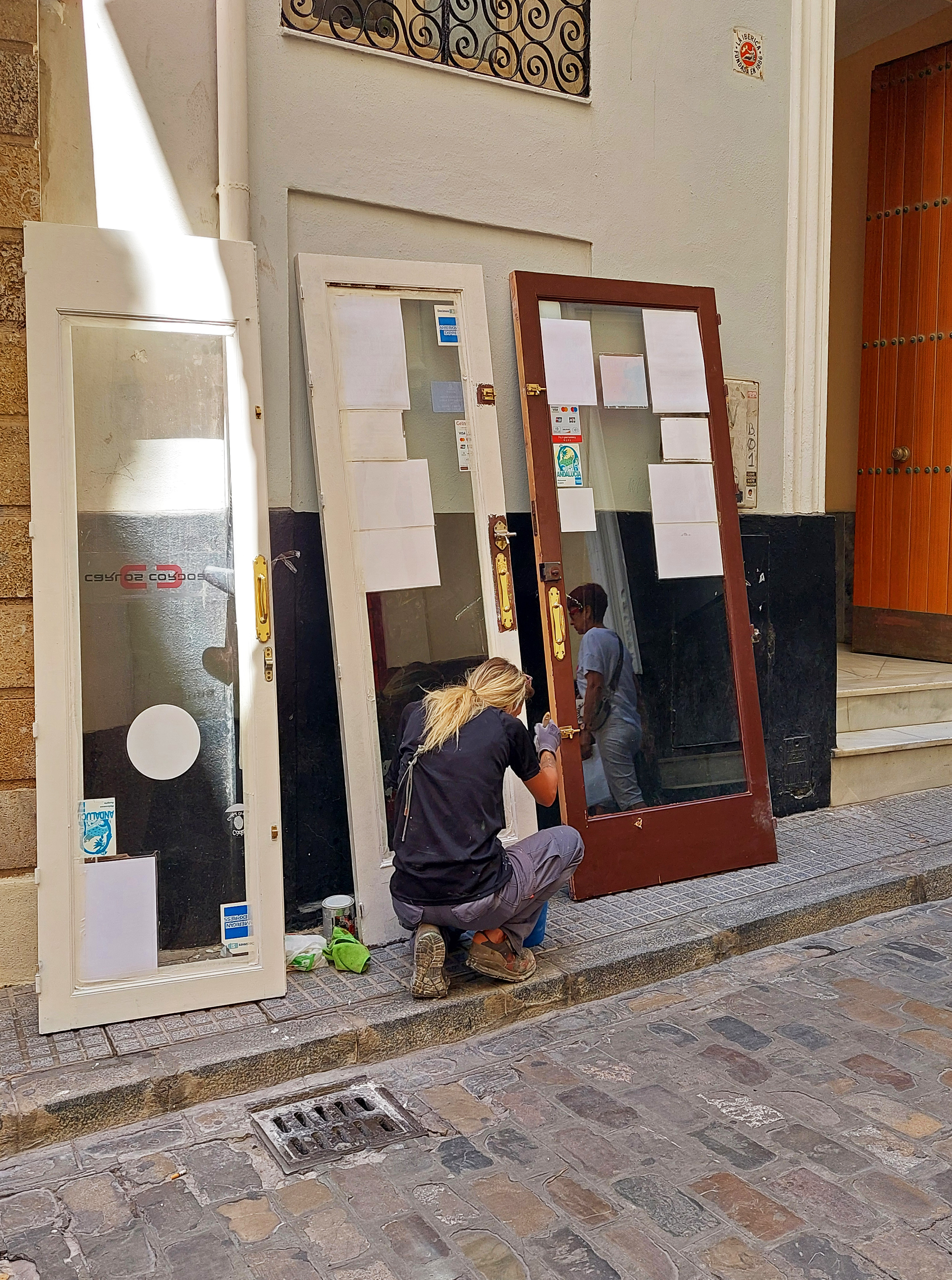 Henkilö maalaa ovea kadulla